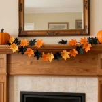 Colorful DIY Halloween garland draped across a fireplace mantel featuring orange pumpkins, black bats, and autumn leaves